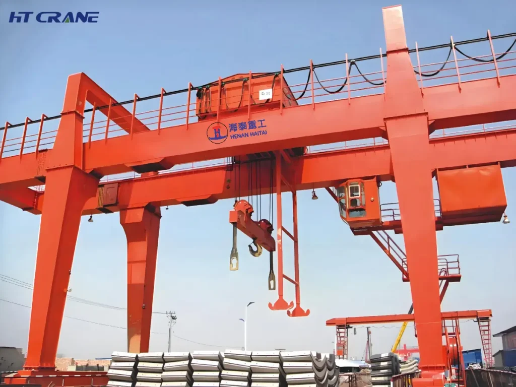 Double girder gantry crane with two parallel main girders lifting curved steel plate sections outdoors
