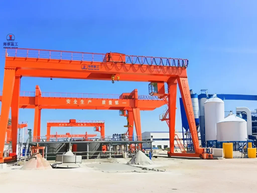 Double girder gantry crane operating at an industrial cement plant with storage silos in the background