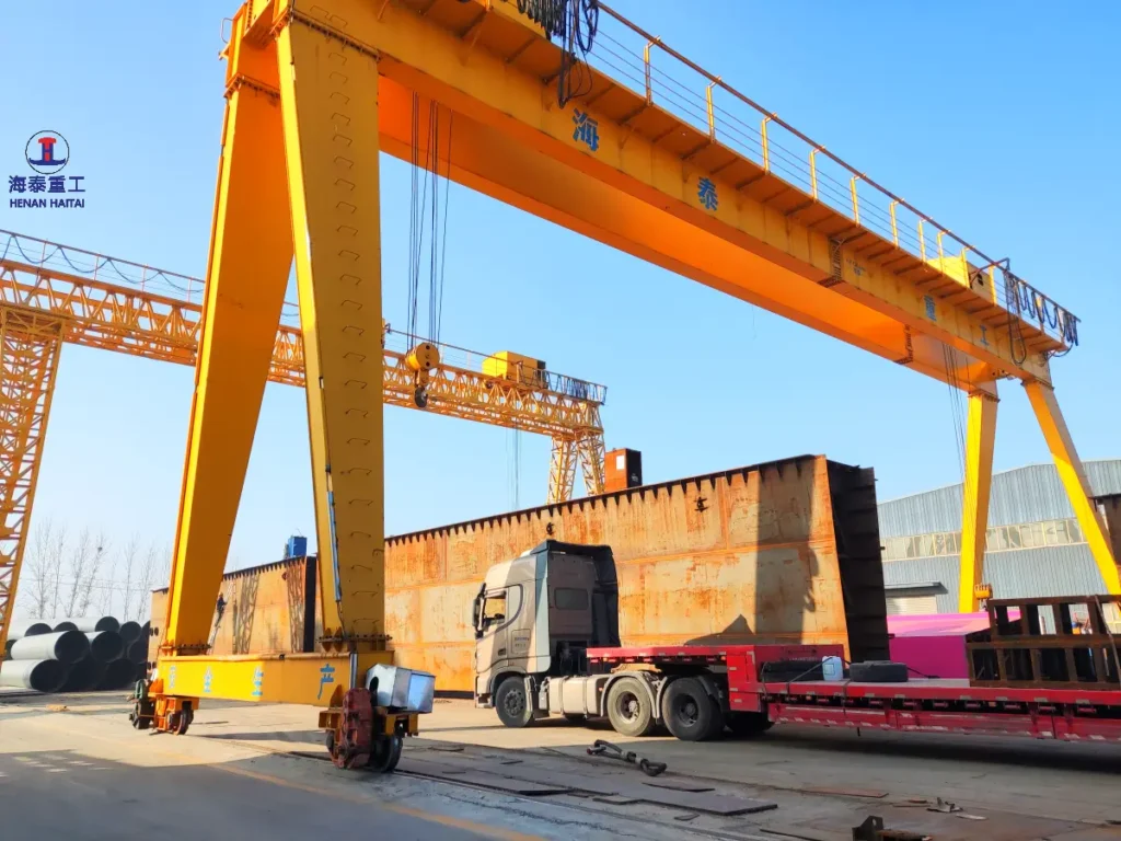 Double girder gantry crane at Haitai's fabrication yard, shown alongside a truss gantry crane and a heavy steel structure loaded on a flatbed truck