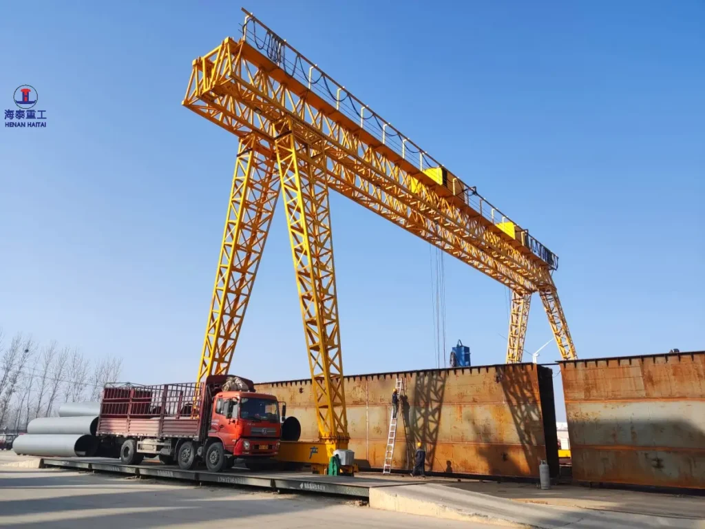 Large single girder gantry crane loading steel plate structures at an outdoor fabrication yard